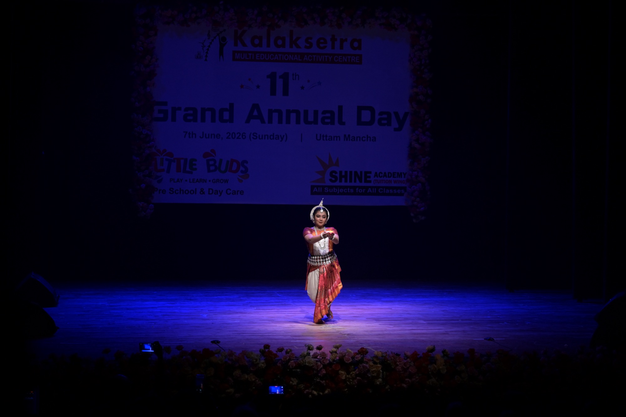 Odissi dancer performing a devotional gesture on a full stage