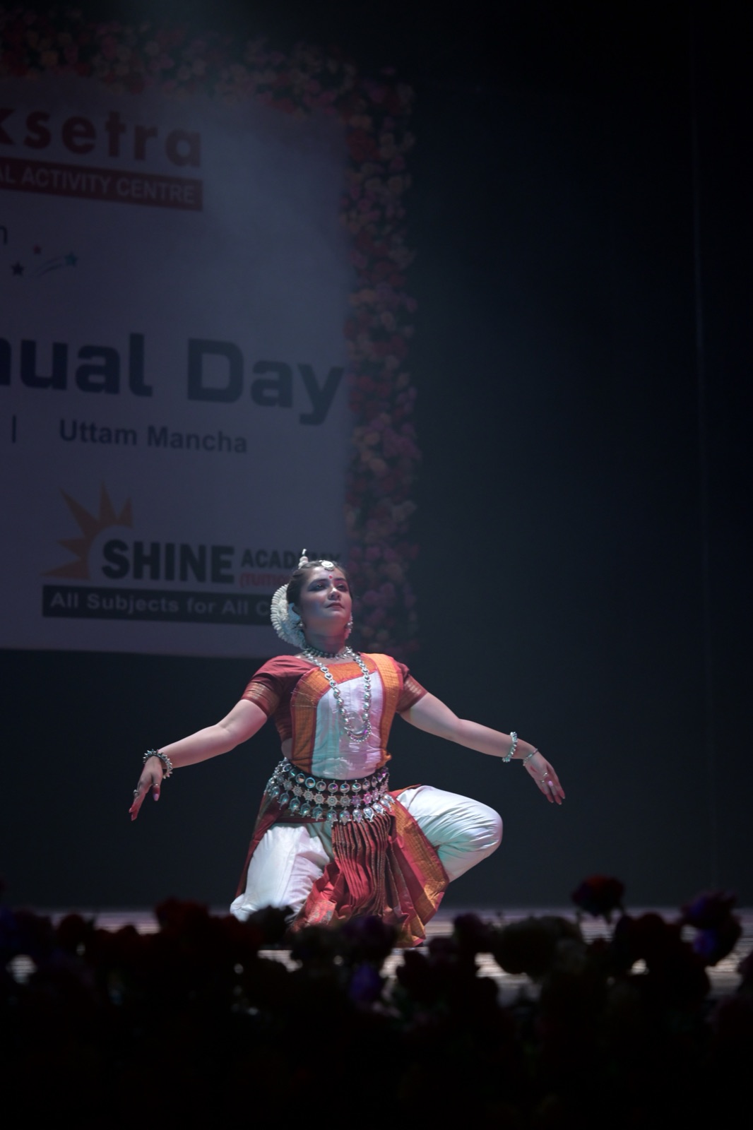 Odissi dancer in a sculptural pose against a stage backdrop